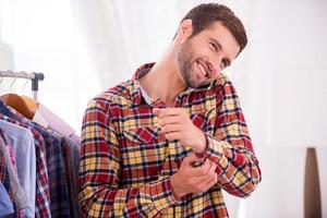 Wearing his favorite shirt. Handsome young man wearing shirt and talking on the mobile phone photo