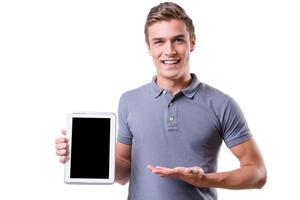 copie el espacio en su tableta. un joven apuesto que sostiene una tableta digital y la señala con una sonrisa mientras se encuentra aislado de fondo blanco foto