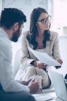 There is no signature here Close-up part of young beautiful woman pointing at documents in her hand while sitting on the couch at office with her coworkers photo