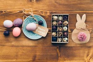 Easter vibes. Top view of colored Ester eggs on plate and Easter decorations lying on wooden rustic table photo