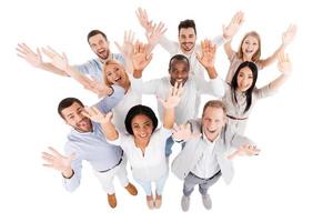 Successful business team. Top view of positive diverse group of people in smart casual wear looking at camera and stretching out their hands while standing close to each other photo