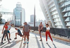 Full length of people in sports clothing warming up and stretching while exercising outdoors photo