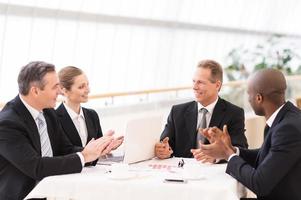 Good job done. Business people in formalwear sitting together at the table and applauding photo