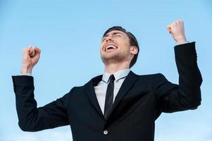 Successful businessman. Happy young man in suit gesturing while standing outdoors photo