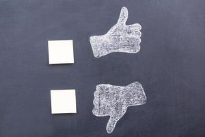 Yes or no Blackboard drawing of thumbs up and down with adhesive notes near them photo