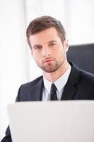 Confident businessman. Confident young man in formalwear looking at camera while sitting at his working place photo