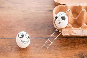 Love has no barriers. Top view of funny egg flirting with female egg laying in container and on the wooden desk photo