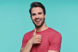 Handsome young man in casual clothing looking at camera and showing his thumb up photo