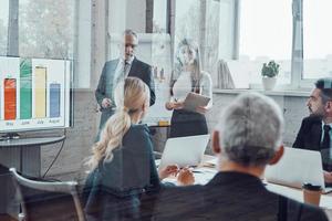 Modern businessman conducting presentation and analyzing data on the graph while having staff meeting in the board room photo