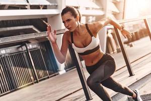 Beautiful young woman in sports clothing running while exercising outdoors photo