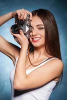 She likes photographing. Beautiful young woman focusing with camera and smiling photo