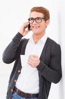 Nice talk. Handsome young man drinking coffee and talking on the mobile phone while standing indoors photo