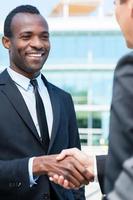 Business people shaking hands. Two business men shaking hands and smiling while standing outdoors photo