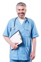 Cheerful surgeon. Cheerful mature doctor looking at camera and smiling while holding clipboard and standing isolated on white photo