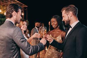 Group of people in formalwear communicating and smiling while spending time on luxury party photo