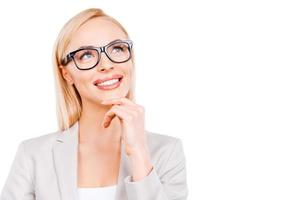 In searching of new ideas. Thoughtful mature businesswoman holding hand on chin and smiling while standing against white background photo