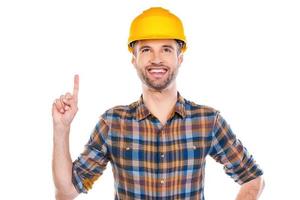 Look at that Confident young male carpenter pointing up and smiling while standing against white background photo