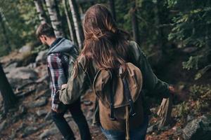 Best way to escape from the city. Rear view of young couple hiking together in the woods while enjoying their travel photo