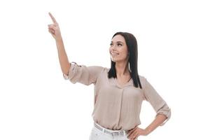 Look over there Attractive young woman in smart casual wear pointing away and smiling while standing against white background photo