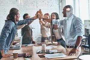 High-five Group of business colleagues giving each other high-five while working behind the glass wall in the board room photo