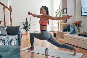 Sensual young woman in sports clothing working out while spending time at home photo