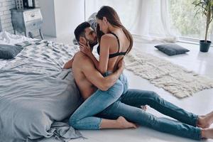 intimidad. hermosa joven pareja semi-vestida uniéndose mientras pasa tiempo en casa foto