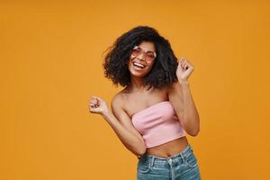 Beautiful young African woman in casual clothing dancing and looking at camera with smile photo