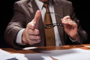 Welcome on board. Cropped image of man in formalwear sitting at his working place and stretching out his hand for shaking while isolated on black background photo