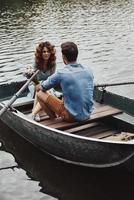 haciendo recuerdos felices. hermosa pareja joven disfrutando de una cita romántica mientras rema en un bote foto