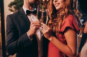 Close up of beautiful young couple in formalwear toasting with champagne while spending time on luxury party photo