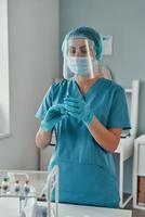 Young female paramedic in protective workwear holding a Covid-19 vaccine while working in the hospital photo