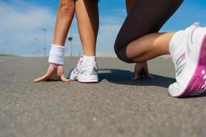 listo para correr. imagen de primer plano de una mujer con zapatos deportivos parada en la línea de salida foto