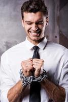 Businessman trapped in chains. Frustrated young businessman grimacing while being trapped in chains photo