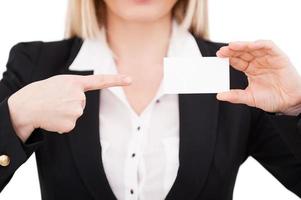 Copy space on business card. Cropped image of businesswoman pointing her business card while standing isolated on white photo