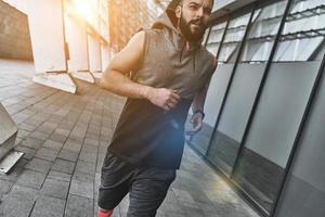 On the move. Handsome young man in sport clothing looking away while running outside photo