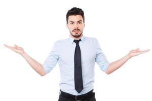 So hard to choose Frustrated young man in shirt and tie holding copy spaces in both hands and looking at camera while standing against white background photo