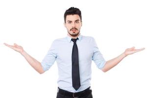 So hard to choose Frustrated young man in shirt and tie holding copy spaces in both hands and looking at camera while standing against white background photo