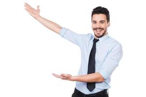 It is unbelievable Happy young man in shirt and tie pointing away and smiling while standing against white background photo