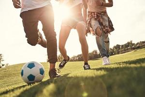 primer plano de jóvenes con ropa informal corriendo mientras juegan al fútbol al aire libre foto