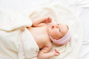 She is so cute top view of little baby lying in bed and looking away photo