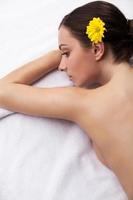 Spa girl. Top view of attractive young woman with flower in head lying down and looking away photo
