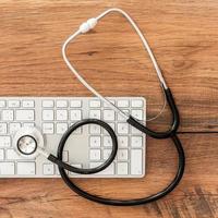 Salvation of computer. Top view of keyboard and stethoscope laying on the wooden grain photo