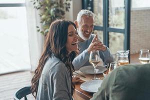 Happy family communicating and smiling while having dinner together photo
