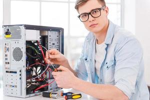 profesional inteligente. retrato de un joven apuesto que repara una computadora mientras está sentado en su lugar de trabajo foto