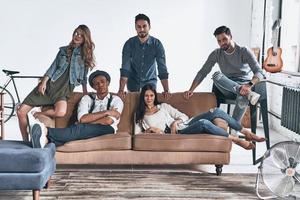 Best friends.  Group of happy young people in casual wear looking at camera and smiling while resting at home photo