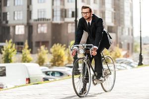 Cycling is the way to progress Full length of handsome young businessman looking forward while riding on his bicycle photo