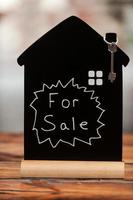 House for sale. Close-up of toy house with key hanging on it photo