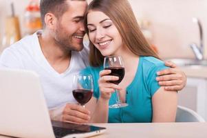Romantic moments. Beautiful loving couple sitting at the laptop and drinking wine photo