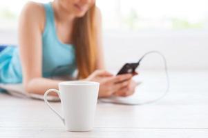 relajándose con su música favorita. imagen recortada de una adolescente con auriculares escuchando música y tumbada en el suelo de su apartamento foto