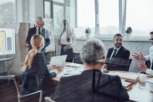 hombre de negocios seguro de sí mismo realizando una presentación mientras se reúne el personal en la sala de juntas foto